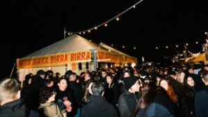 Ragazzi ad una manifestazione all'aperto davanti ad un ambulante che vende street food e birra